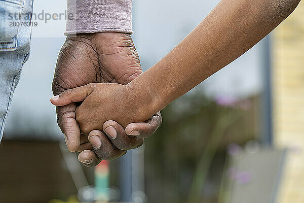 Nigerianischer Vater und Sohn halten sich an den Händen. Bedingungslose Liebe