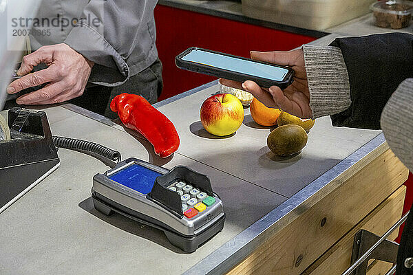 Erwachsene Frau bezahlt Obst und Gemüse.