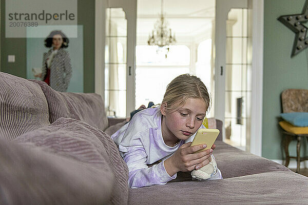 Junger Teenager entspannt sich auf dem Sofa und recherchiert mit ihrem Telefon