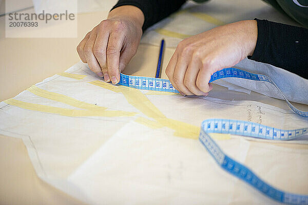 Female fashion designer working on fabric designs in her workshop. Concentrating on patterns and design. Measuring out