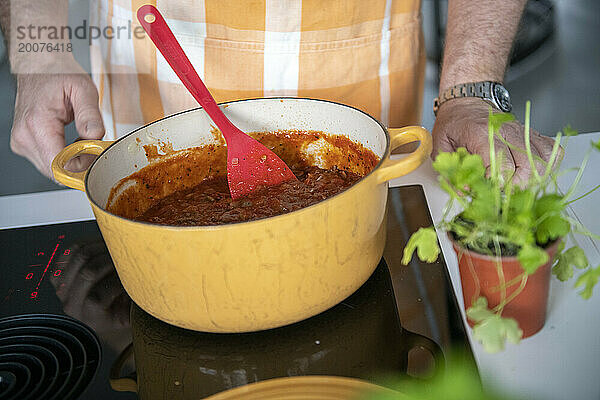 Erwachsener Mann bereitet in seiner modernen Küche Hackfleisch für eine Lasagne zu