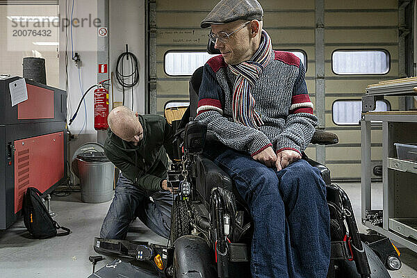 Mechanic working on mans prototype wheelchair