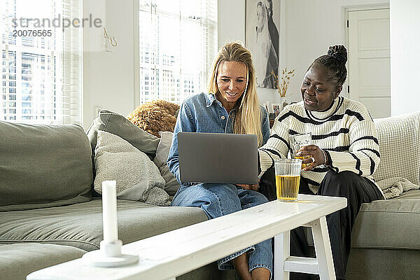 Freunde sitzen zusammen mit ihrem Laptop auf dem Sofa und planen einen Urlaub