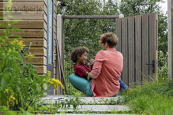 Mutter und Sohn gemischter Abstammung spielen gemeinsam im Garten und lachen