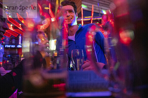 Alkoholische Getränke im Fokus  glücklicher und feiernder Mann im Hintergrund. Neon