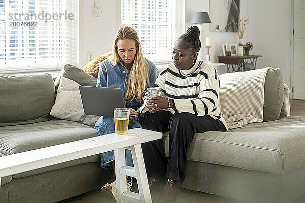 Freunde sitzen zusammen mit ihrem Laptop auf dem Sofa und planen einen Urlaub