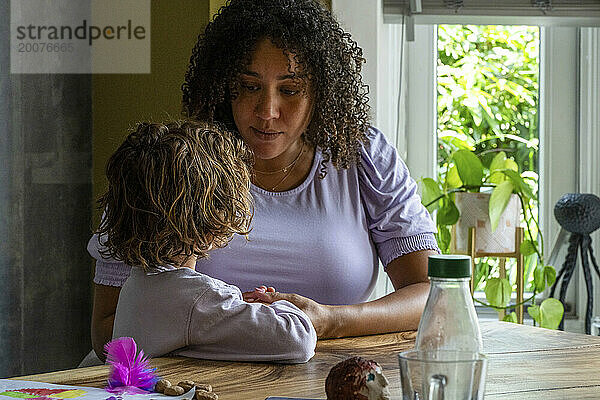 Afroamerikanische Frau sitzt mit ihrem Sohn am Tisch