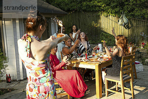 Eine gemischte Zusammenkunft von Frauen  die bei einer Sommergarten-Geburtstagsfeier zum Mittagessen lachen und Spaß haben