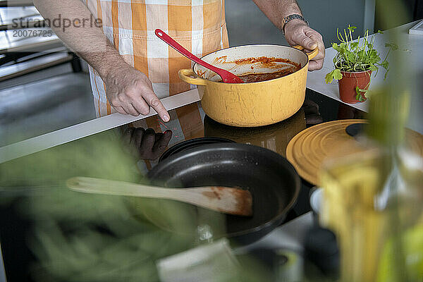 Erwachsener Mann bereitet in seiner modernen Küche Hackfleisch für eine Lasagne zu