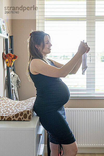 Schwangere Mutter freut sich  neue Kleidung für das Baby zu öffnen