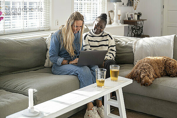 Freunde sitzen zusammen mit ihrem Laptop auf dem Sofa und planen einen Urlaub