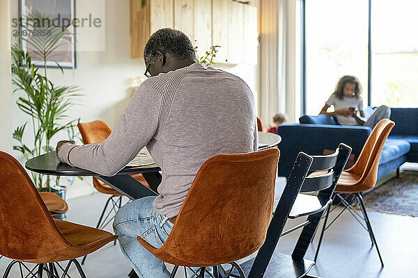 Eltern gemischter Abstammung sitzen am Küchentisch und diskutieren über das Leben  Rechnungen und die Organisation des Familienlebens. Entspannen Sie sich bei einer Tasse Kaffee