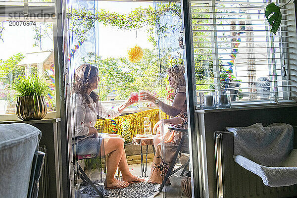Zwei Freunde sitzen an einem Sommertag auf dem Balkon  trinken Cocktails und nehmen ein gesundes Mittagessen in der Sonne ein