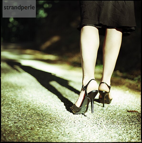 Frau trägt High Heels draußen  Schatten
