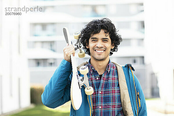 Junger Mann mit Skateboard  der draußen trägt