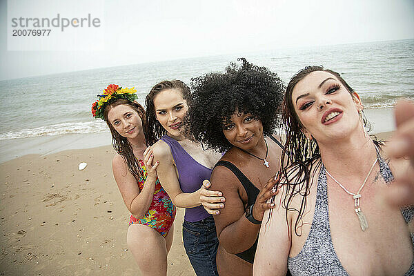 Gemischte Gruppe von Freundinnen  die Spaß am Strand haben und Selfies machen.