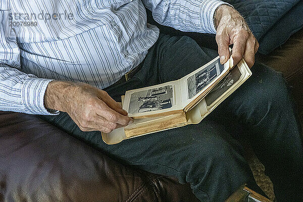 Nahaufnahme eines älteren Mannes  der alte Fotos seiner Frau betrachtet