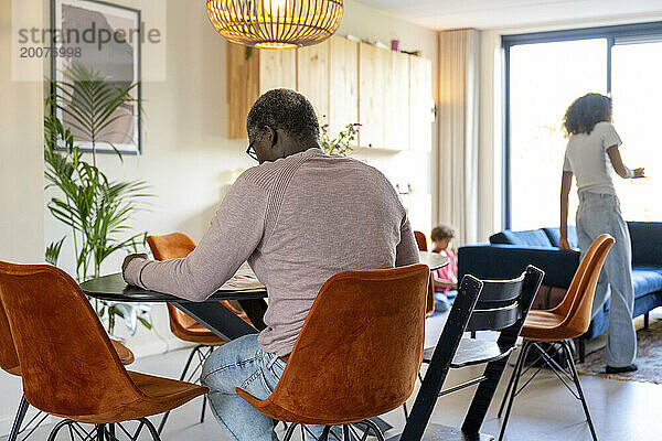 Eltern gemischter Abstammung sitzen am Küchentisch und diskutieren über das Leben  Rechnungen und die Organisation des Familienlebens. Entspannen Sie sich bei einer Tasse Kaffee