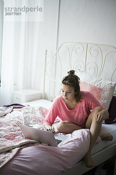 Teenager-Mädchen lernt im Bett mit ihrem Laptop