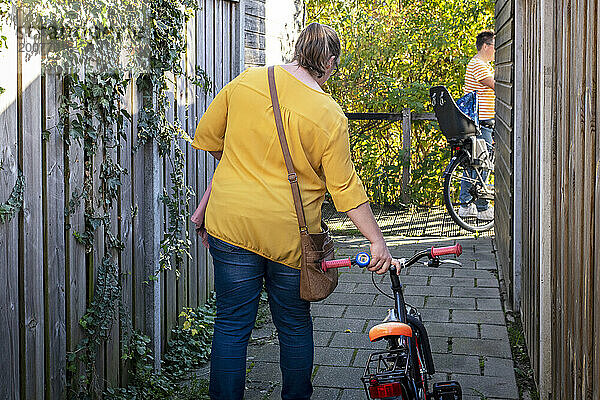 Gleichgeschlechtliche Eltern bereiten ihre Kinder darauf vor  für den Tag auszugehen. Sie schieben ihre Fahrräder
