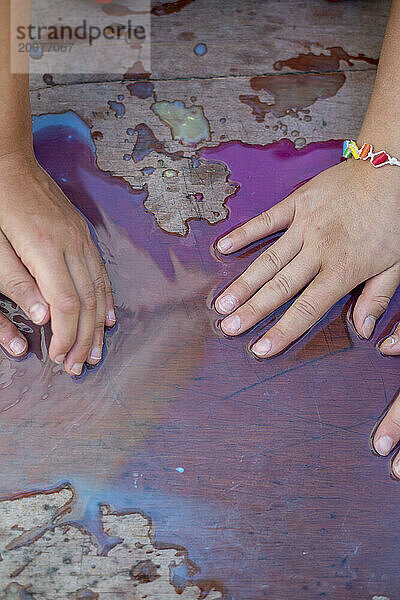Junge Mädchen mit ihren Händen in Wasserfarben haben Spaß