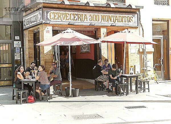 Fröhliche Menschen winken vor einer traditionellen Cerveceria Bar im Zentrum von Sevilla  Spanien  Europa