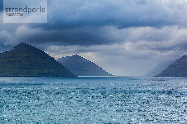 Küstenlinie der Färöer Inseln bei bedecktem und dramatischem Himmel