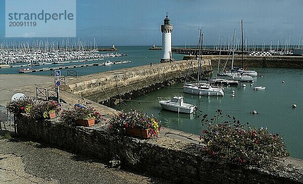 Ein ruhiger Yachthafen mit einem Leuchtturm an einem teilweise bewölkten Tag Quiberon Bretagne