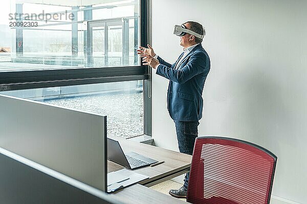 Geschäftsmann stehend mit 3D Brille bei der Arbeit im Büro mit Blick auf die Fenster