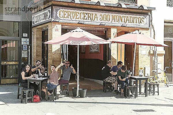 Fröhliche Menschen winken vor einer traditionellen Cerveceria Bar im Zentrum von Sevilla  Spanien  Europa