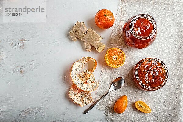 Mandarinen und Kumquatmarmelade in einem Glas mit frischen Früchten auf weißem Holzhintergrund. Hausgemacht  Kopierraum  Draufsicht