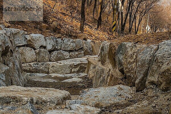 Aus großen Felsblöcken gebauter Entwässerungsgraben an der Seite eines Berges am frühen Frühlingsnachmittag in Südkorea