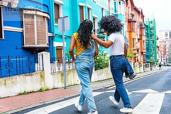 Rückansicht von zwei afroamerikanischen jungen Freunden  die eine bunte Straße entlanggehen