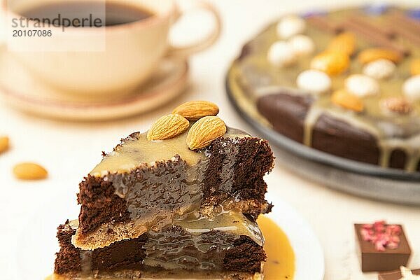 Stücke von Schokoladen Brownie Kuchen mit Karamellcreme und Mandeln auf einem weißen Betonhintergrund. Seitenansicht  Nahaufnahme  selektiver Fokus