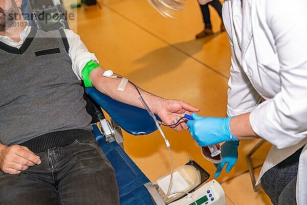 Ausgeschnittenes Foto mit unkenntlichen Menschen  die in einem Spendezentrum Blut in einen Beutel füllen