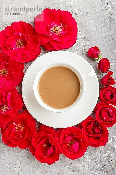 Rote Rosenblüten in einer Spirale und eine Tasse Kaffee auf einem grauen Betonhintergrund. Morninig  Frühling  Mode Zusammensetzung. Flachlage  Draufsicht  Nahaufnahme