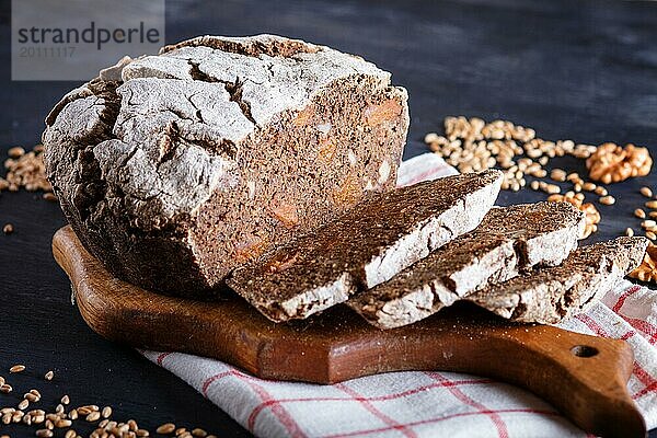 Hefefreie hausgemachte Brotscheiben mit Roggen und Weizenkörnern auf schwarzem Holzhintergrund. Nahaufnahme  selektiver Fokus