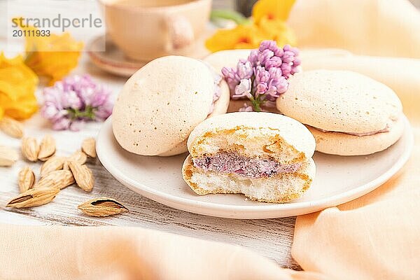 Meringues Kuchen mit einer Tasse Kaffee auf einem weißen Holzhintergrund und orangefarbenem Leinenstoff. Seitenansicht  Nahaufnahme  selektiver Fokus