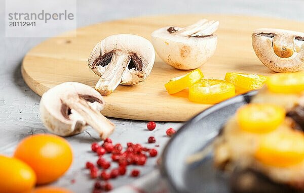 In Scheiben geschnittene rohe Champignons mit Kumquats auf einem grauen Betonhintergrund. Keramikplatte  Seitenansicht  Nahaufnahme  selektiver Fokus