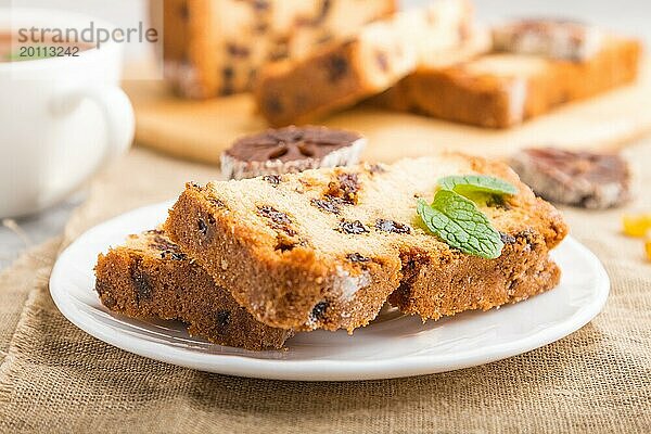 Hausgemachter Kuchen mit Rosinen  getrockneten Kaki und einer Tasse heißer Schokolade auf einem grauen Betonhintergrund und Leinenstoff. Seitenansicht  Nahaufnahme  selektiver Fokus