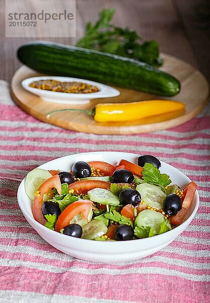 Vegetarischer Salat aus Tomaten  Gurken  Petersilie  Oliven und Senf auf Leinentischdecke  Nahaufnahme  selektiver Fokus
