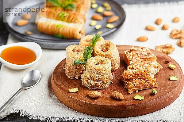 Set verschiedener traditioneller arabischer Süßigkeiten: Baklava  Kunafa  Basbus in Keramiktellern auf grauem Betonhintergrund. Seitenansicht  selektiver Fokus