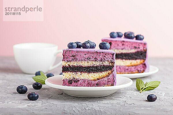 Hausgemachter Kuchen mit Soufflé Creme und Blaubeermarmelade mit Tasse Kaffee und frischen Blaubeeren auf grauem und rosa Hintergrund. Seitenansicht  selektiver Fokus  Nahaufnahme