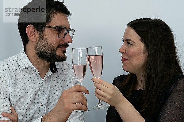 Attraktives Paar stößt mit einem Glas Champagner lächelnd auf ihren Jahrestag an