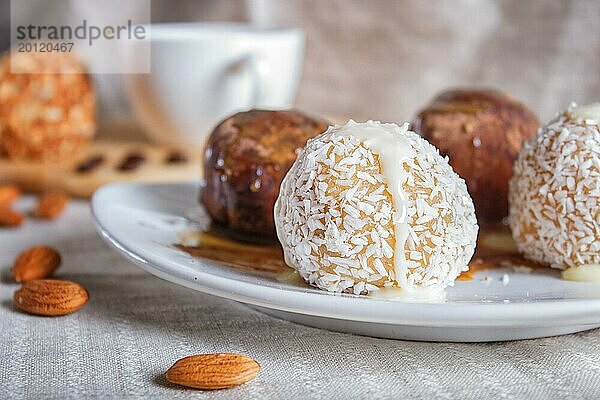 Energiekugeln Kuchen mit Schokolade Karamell und Kokosnuss auf weißem Teller auf Leinen Serviette  selektiver Fokus  Nahaufnahme