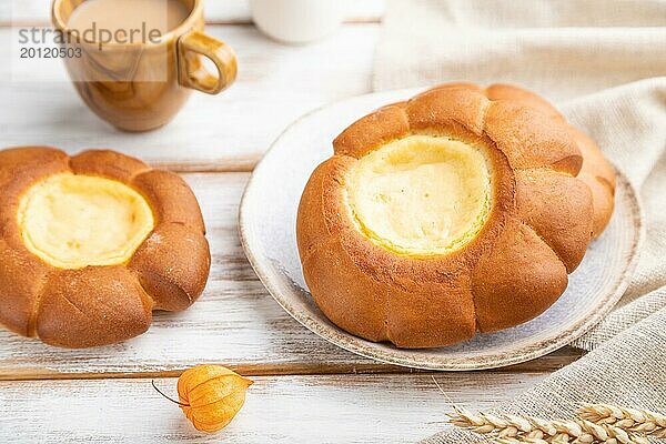 Saures Sahnebrötchen mit Tasse Kaffee auf weißem Holzhintergrund und Leinenstoff. Seitenansicht  Nahaufnahme  selektiver Fokus