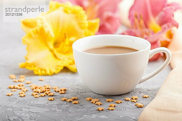 Gelbe und lila Taglilien Tasse Kaffee auf einem grauen Hintergrund Beton  mit orangefarbenen Textil. Morninig  Frühling  Mode Zusammensetzung  Seitenansicht  Nahaufnahme  selektiver Fokus