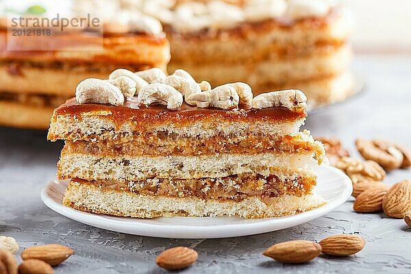 Ein Stück hausgemachter Kuchen mit Karamellcreme und Nüssen auf einem grauen Betonhintergrund. Seitenansicht  Nahaufnahme  selektiver Fokus