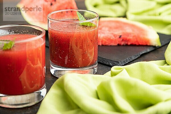 Wassermelonensaft mit Chiasamen und Minze im Glas auf einem schwarzen Betonhintergrund mit grünem Textil. Gesundes Getränk Konzept. Seitenansicht  Nahaufnahme  selektiver Fokus