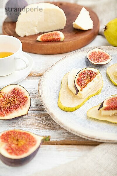 Sommerliche Vorspeise mit Birne  Hüttenkäse  Feigen und Honig auf einem weißen Holzhintergrund und Leinenstoff. Seitenansicht  Nahaufnahme  selektiver Fokus